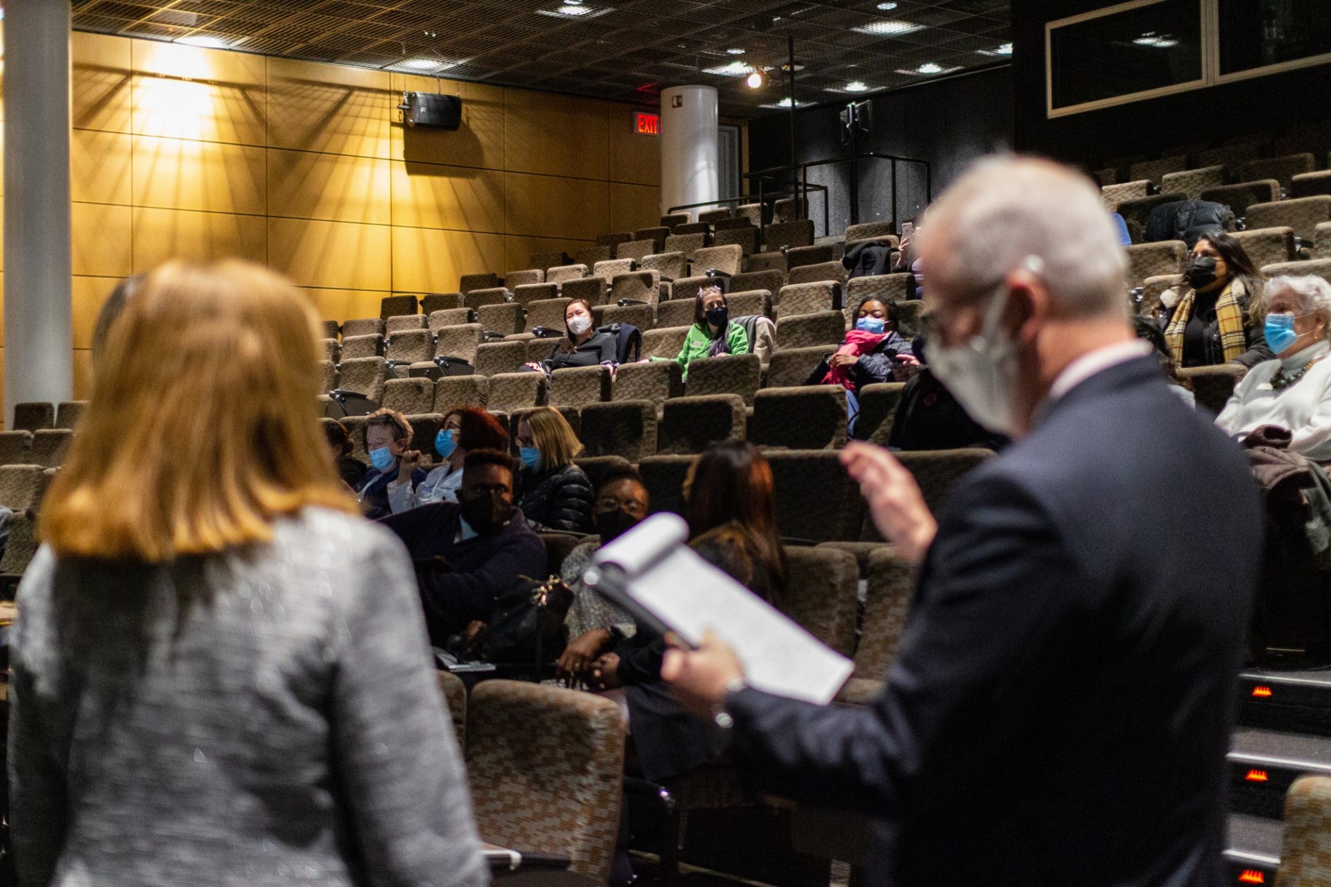 Shot of audience with two individuals out of focus in the foreground