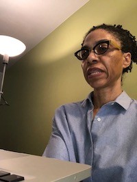 Woman wearing glasses speaking while sitting in front of a desk 