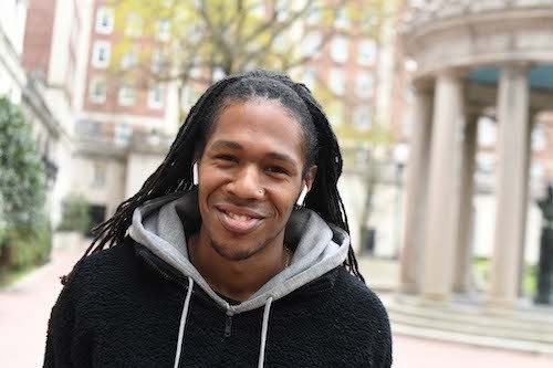 Individual with a braid hairstyle smiling looking at camera