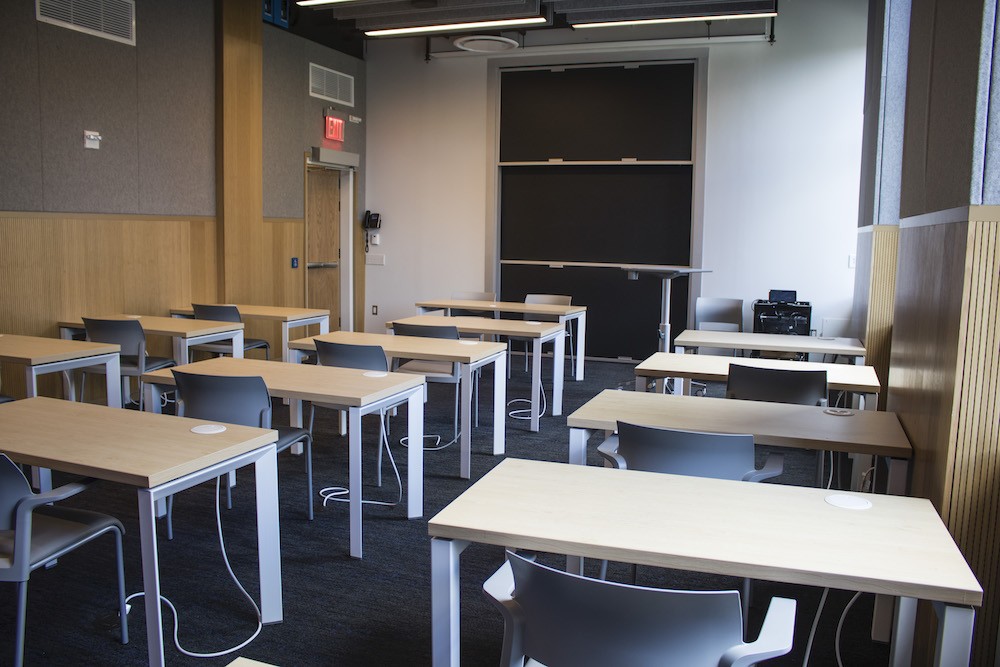 Three rows of desks with chairs and a blackboard