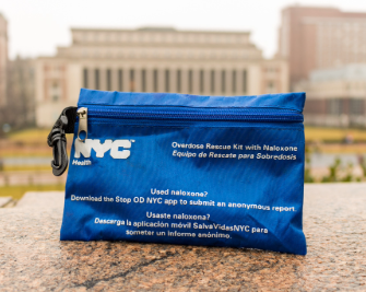blue naloxone kit sitting on ledge with campus buildings in background