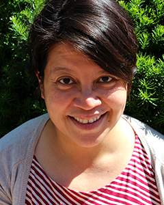 Individual with short hair smiling into camera