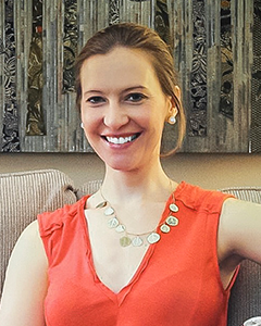 Individual with hair tied back smiling into camera