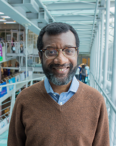 Individual with glasses smiling into camera