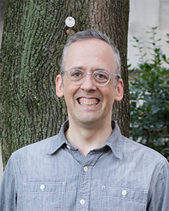 Individual wearing glasses smiling at camera